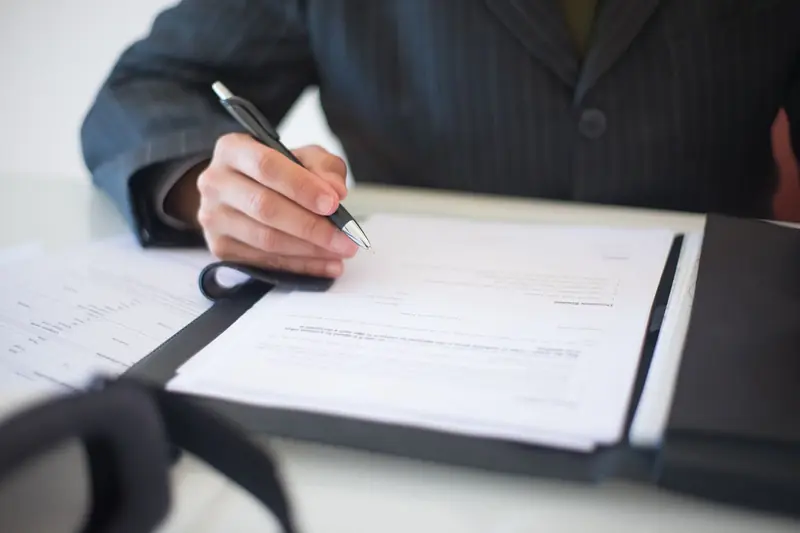 A person signing a contract document with a pen