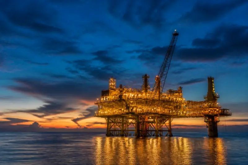 Offshore oil platform illuminated at blue hour