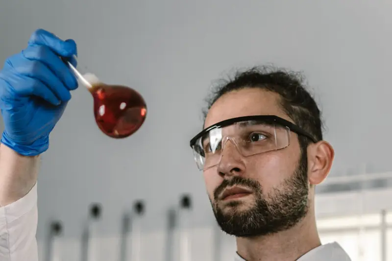 A laboratory technician examining a liquid sample in a glass flask