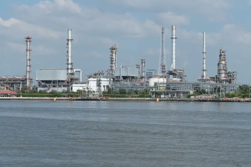 A refinery on a waterfront under a cloudy sky